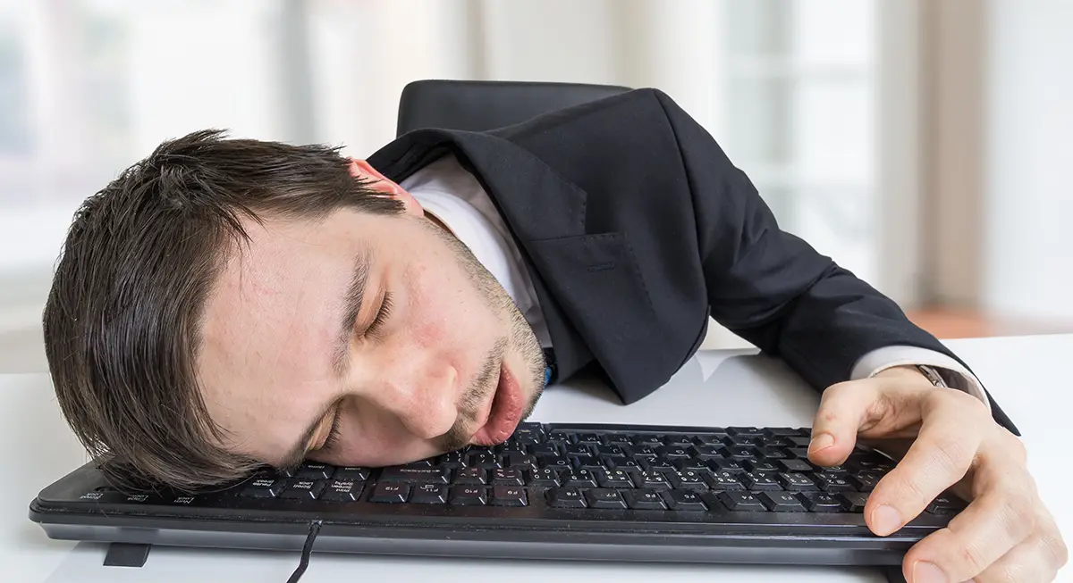 Exhausted or tired businessman is sleeping on keyboard in office.